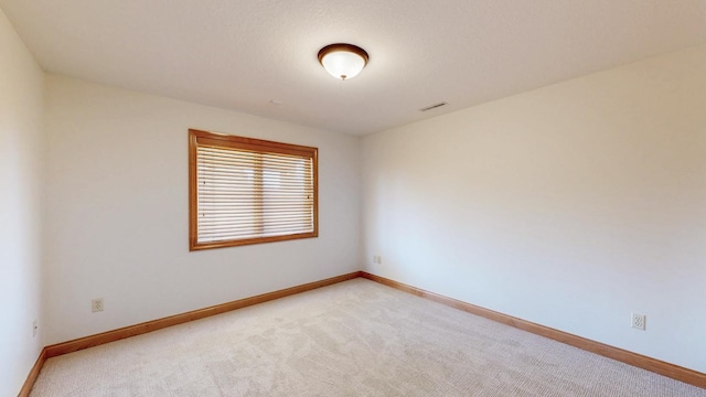 spare room featuring light colored carpet, baseboards, and visible vents