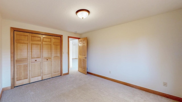 unfurnished bedroom featuring baseboards, light carpet, and a closet