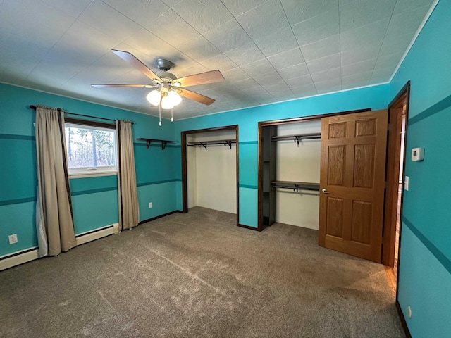 unfurnished bedroom with multiple closets, ceiling fan, baseboard heating, and carpet floors