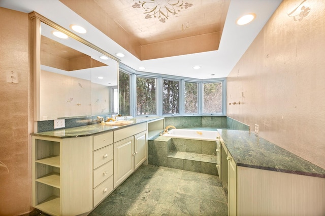 bathroom featuring a relaxing tiled tub, vanity, and a raised ceiling