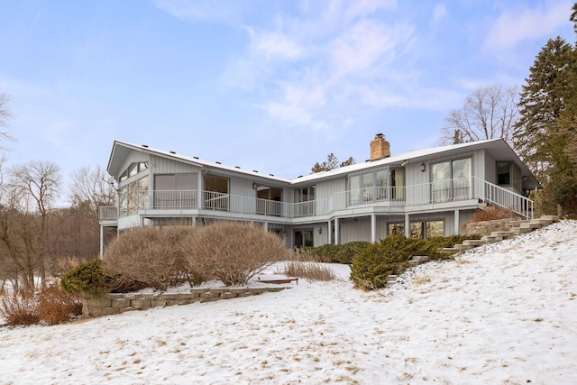 snow covered rear of property with a chimney