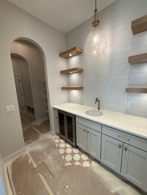 interior space featuring arched walkways, gray cabinets, light countertops, open shelves, and a sink