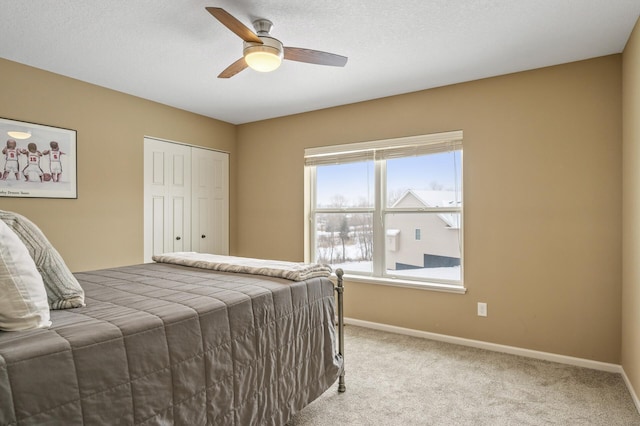 carpeted bedroom with ceiling fan, a textured ceiling, baseboards, and a closet