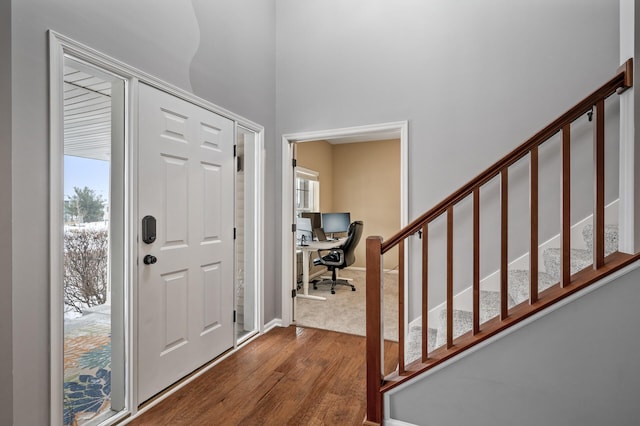 foyer with a healthy amount of sunlight, dark wood-style floors, and stairway