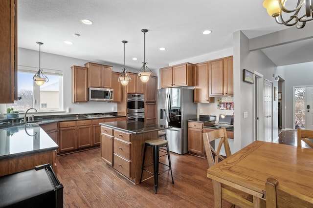 kitchen featuring dark countertops, brown cabinetry, stainless steel appliances, and a sink