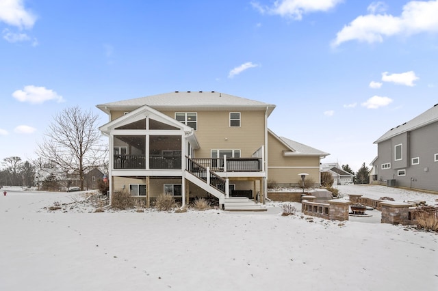 snow covered property with a sunroom, a deck, and stairs