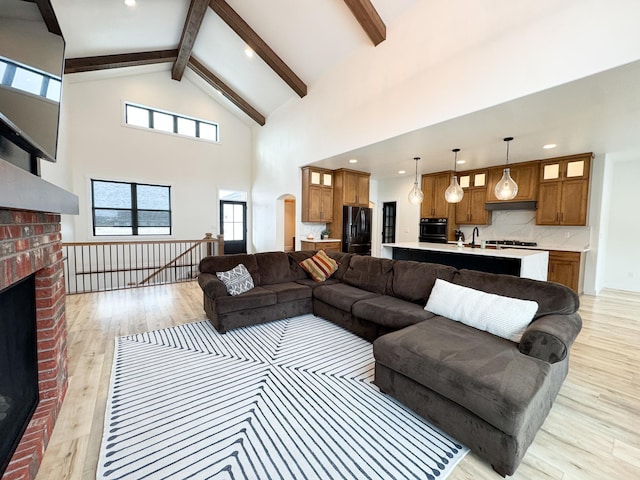 living room featuring beamed ceiling, a fireplace, high vaulted ceiling, and light wood-type flooring