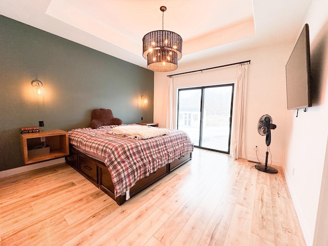 106 19th St NE, Barnesville, MN 56514 - bedroom featuring access to outside, a tray ceiling, light wood finished floors, and a chandelier