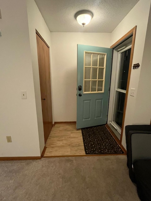 doorway featuring light carpet and a textured ceiling