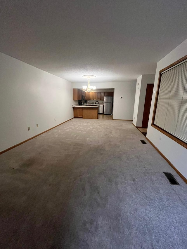 unfurnished living room with an inviting chandelier, carpet, and a textured ceiling