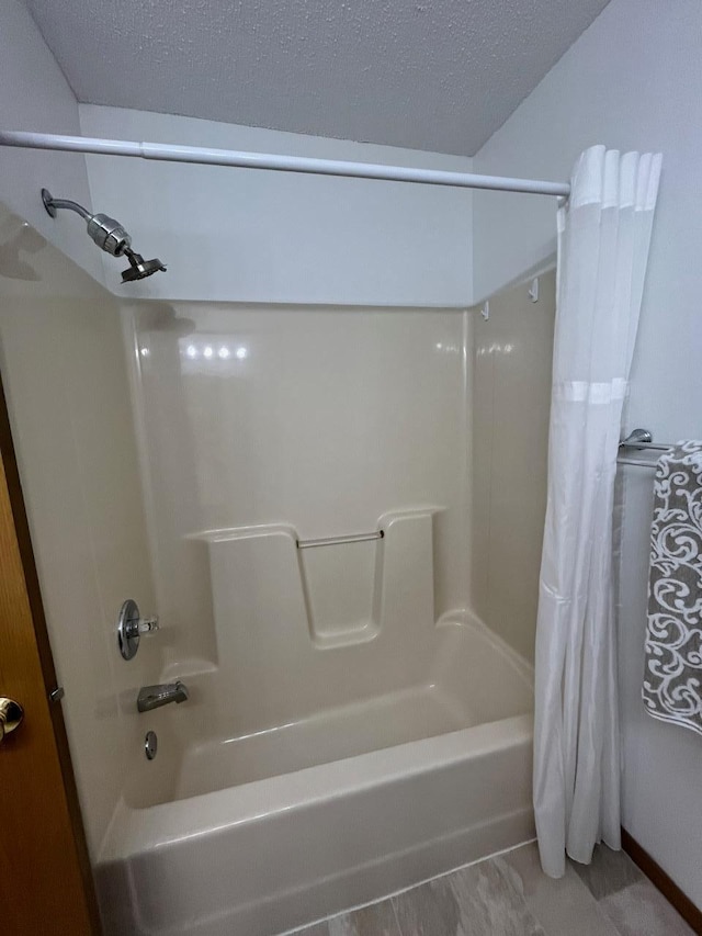 bathroom with shower / bath combo and a textured ceiling