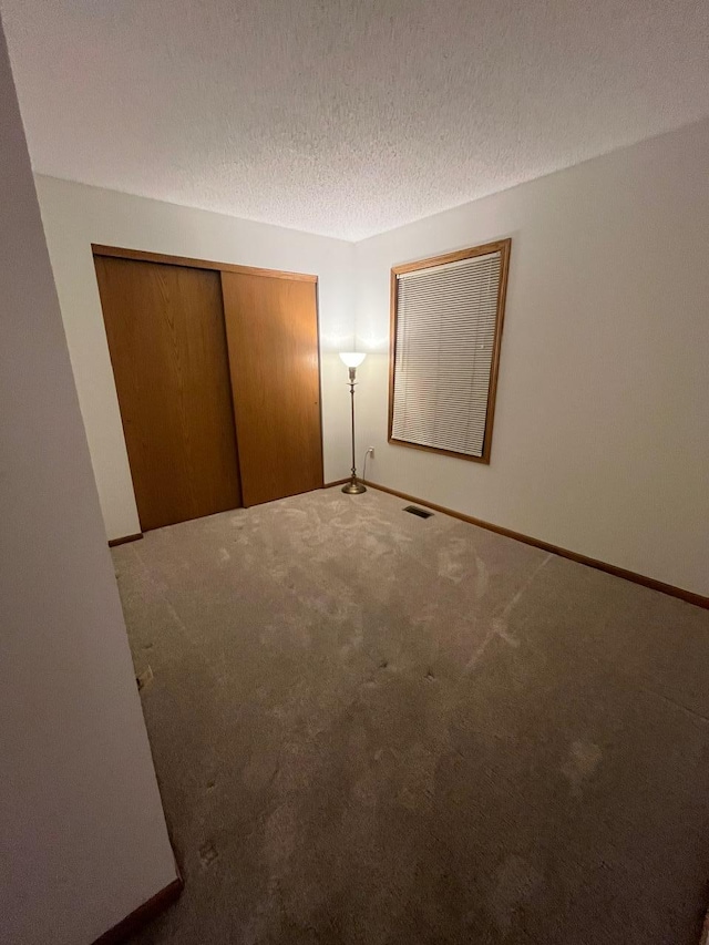 unfurnished bedroom with a closet, carpet flooring, and a textured ceiling