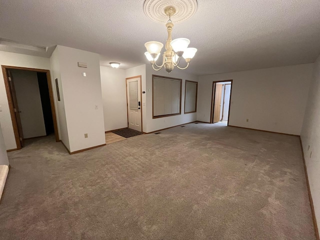 carpeted empty room with a notable chandelier and a textured ceiling