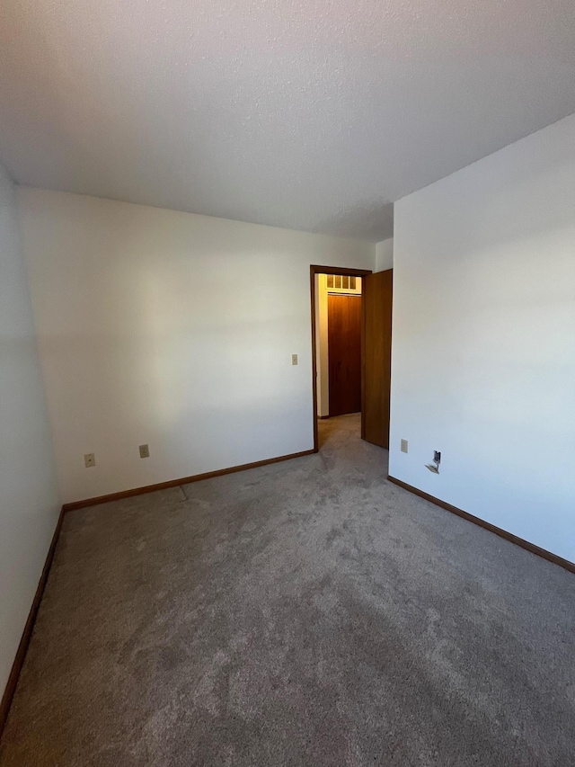 spare room with baseboards, carpet floors, and a textured ceiling