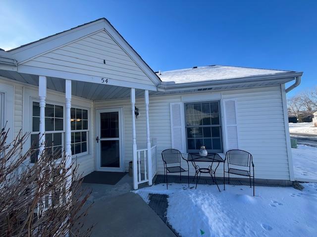 snow covered rear of property with a porch