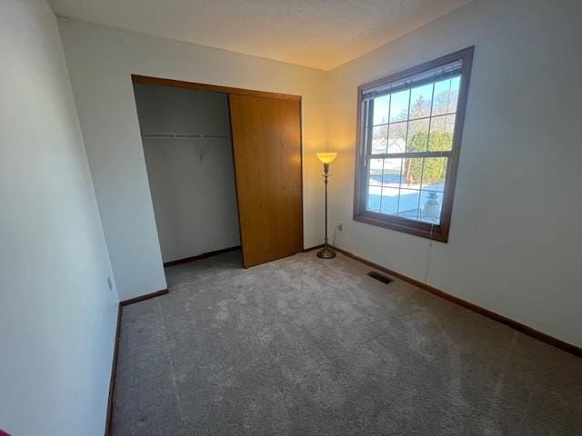 unfurnished bedroom featuring a closet, visible vents, baseboards, and carpet floors