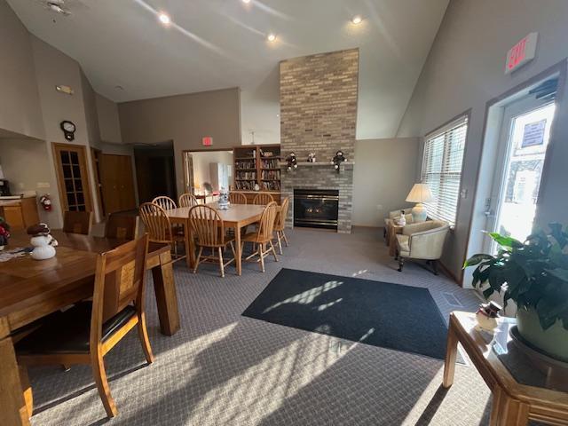 living area with a large fireplace, carpet flooring, and high vaulted ceiling