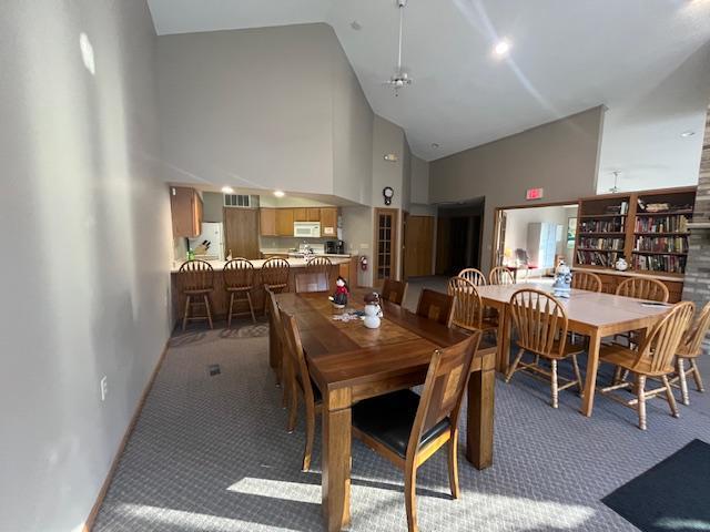 dining room featuring light carpet and high vaulted ceiling