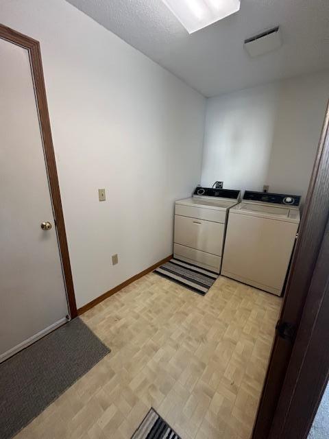 laundry room with laundry area, parquet flooring, baseboards, and washing machine and clothes dryer