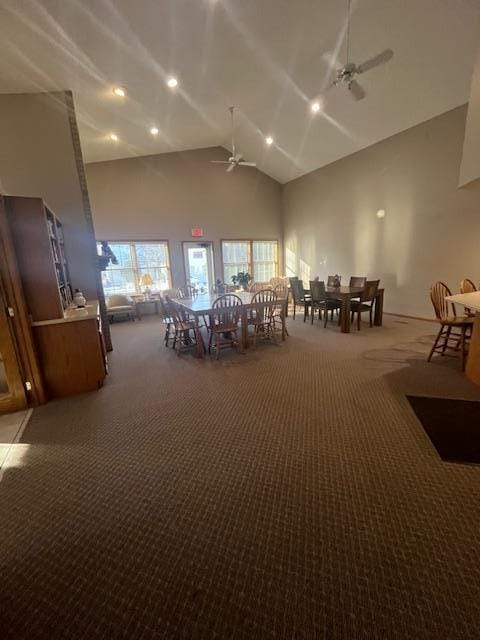 unfurnished dining area with carpet, ceiling fan, and high vaulted ceiling