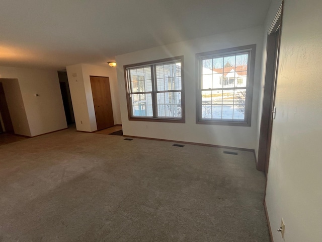 carpeted spare room with visible vents and baseboards