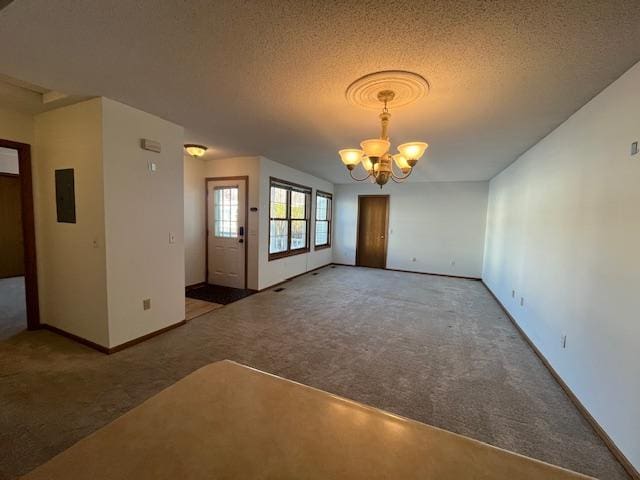 unfurnished living room with baseboards, a textured ceiling, a chandelier, and carpet flooring