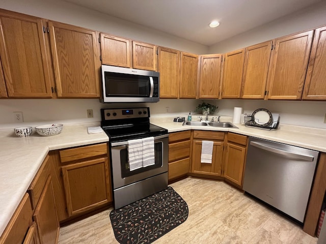 kitchen with light countertops, recessed lighting, appliances with stainless steel finishes, brown cabinetry, and a sink