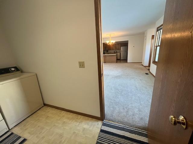 laundry room with baseboards, a chandelier, light colored carpet, laundry area, and washer / clothes dryer