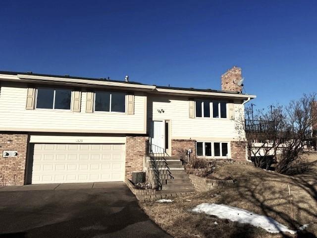 raised ranch featuring a garage and cooling unit