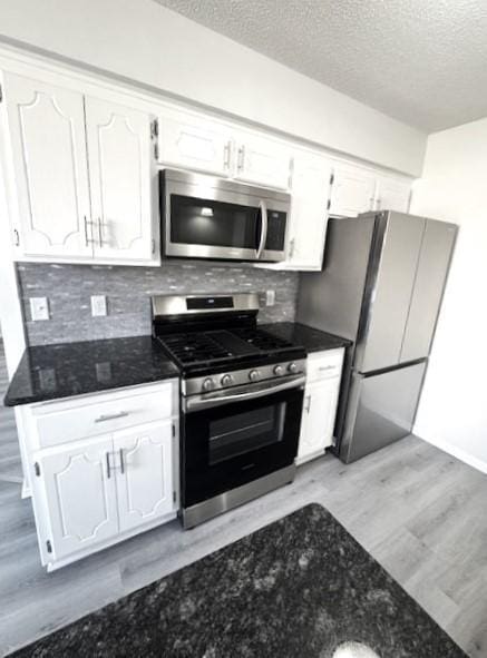 kitchen with stainless steel appliances, decorative backsplash, and white cabinets