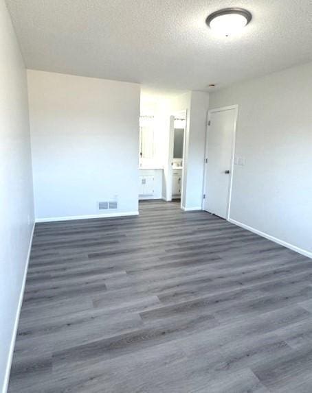 empty room with a textured ceiling and dark hardwood / wood-style flooring