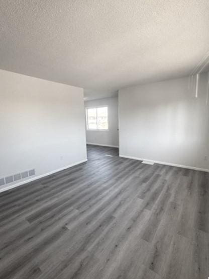 empty room featuring dark wood-type flooring and a textured ceiling