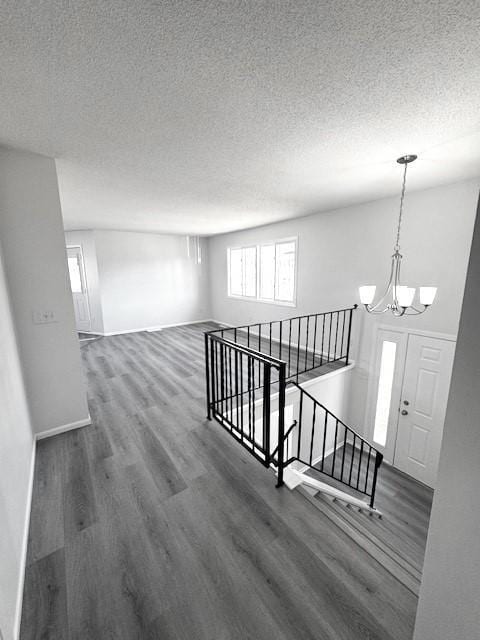 hall with a notable chandelier, dark wood-type flooring, and a textured ceiling