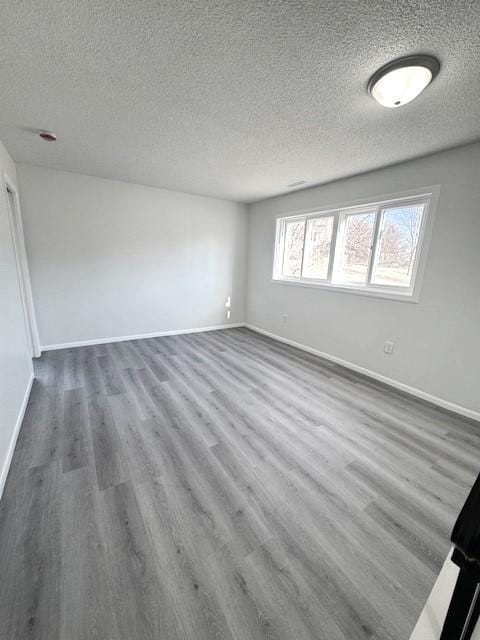 unfurnished room with hardwood / wood-style flooring and a textured ceiling