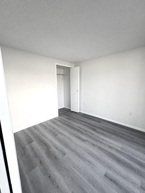 unfurnished bedroom featuring dark wood-type flooring, a closet, and a textured ceiling