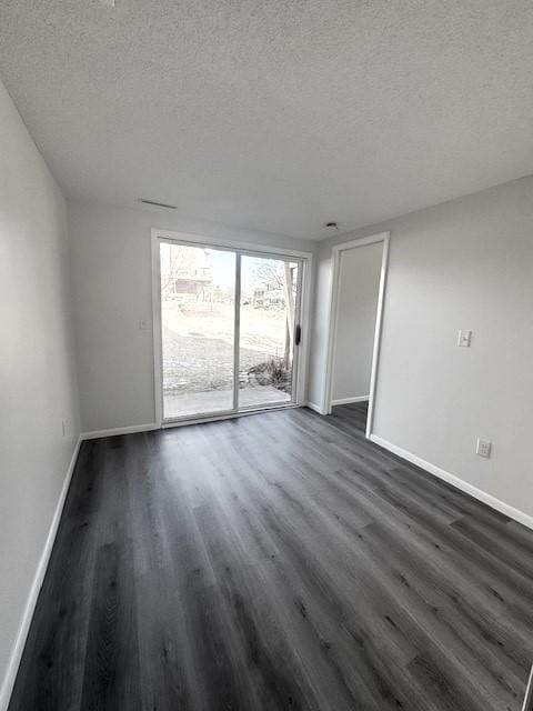 unfurnished room featuring dark wood-type flooring and a textured ceiling