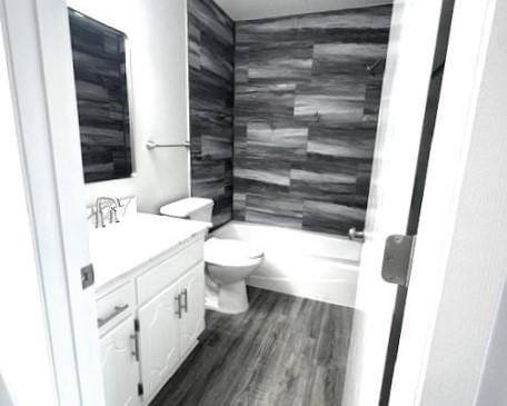 full bathroom with vanity, tiled shower / bath, wood-type flooring, and toilet