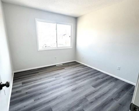 spare room with dark hardwood / wood-style floors and a textured ceiling