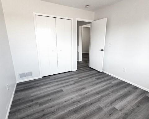 unfurnished bedroom with dark hardwood / wood-style floors and a closet