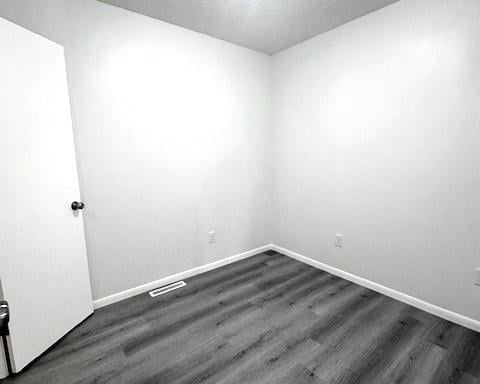 unfurnished room featuring a textured ceiling and dark hardwood / wood-style flooring