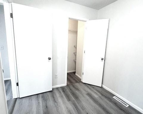 unfurnished bedroom featuring dark hardwood / wood-style flooring, a spacious closet, and a closet