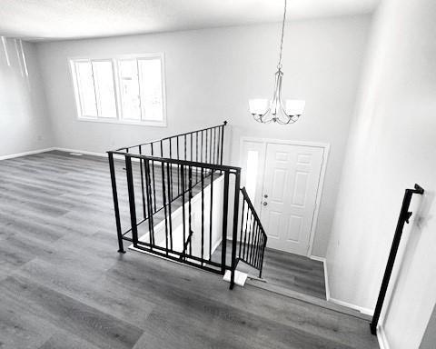 staircase with hardwood / wood-style floors and a chandelier