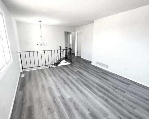 empty room with dark hardwood / wood-style flooring and a chandelier