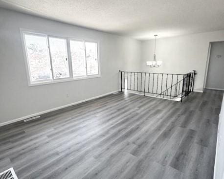 empty room featuring dark hardwood / wood-style flooring, a chandelier, and a textured ceiling