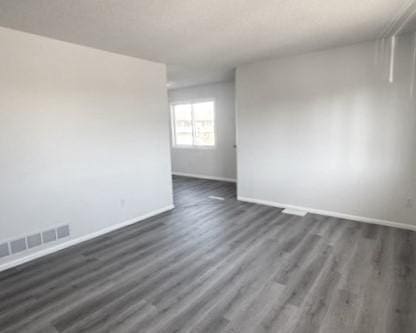 unfurnished room with dark wood-type flooring