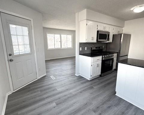 kitchen featuring appliances with stainless steel finishes, dark hardwood / wood-style floors, white cabinets, and decorative backsplash