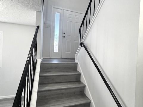 stairs with hardwood / wood-style floors and a textured ceiling