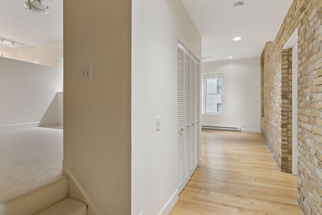 corridor with light hardwood / wood-style flooring and a baseboard radiator