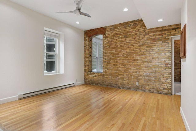 empty room featuring a baseboard heating unit, light hardwood / wood-style floors, ceiling fan, and brick wall