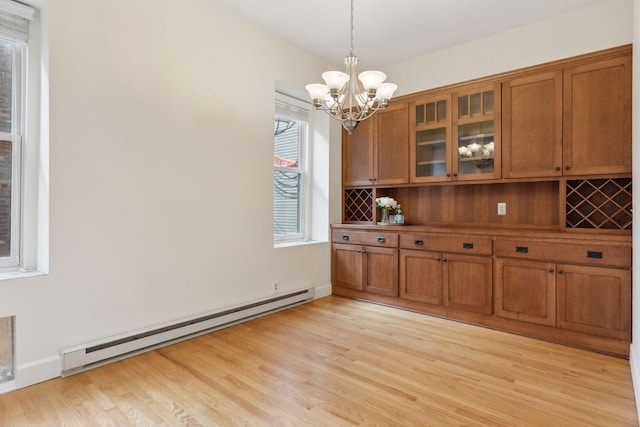 unfurnished dining area with a baseboard heating unit, a notable chandelier, and light hardwood / wood-style floors